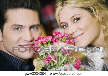 Portrait of a young couple with a bouquet of flowers between them View Large Photo Image Stock Image - Portrait of a young couple with a bouquet of flowers between them. Fotosearch