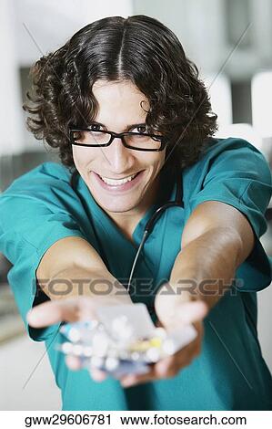 Portrait of a young male doctor holding a blister pack View Large Photo Image Stock Image - Portrait of a young male doctor holding a blister pack. Fotosearch