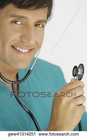 Portrait of a young male doctor wearing a stethoscope and smiling View Large Photo Image Stock Image - Portrait of a young male doctor wearing a stethoscope and smiling. Fotosearch
