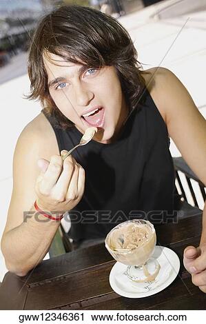 Portrait of a young man eating an ice-cream sundae View Large Photo Image Stock Image - Portrait of a young man eating an ice-cream sundae. Fotosearch