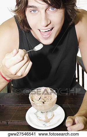 Portrait of a young man eating an ice-cream sundae View Large Photo Image Stock Image - Portrait of a young man eating an ice-cream sundae. Fotosearch