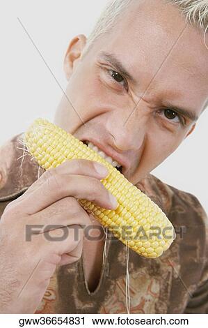 Stock Image - Portrait of a young man eating corn. Fotosearch
