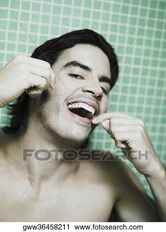 Portrait of a young man flossing his teeth View Large Photo Image Stock Image - Portrait of a young man flossing his teeth. Fotosearch