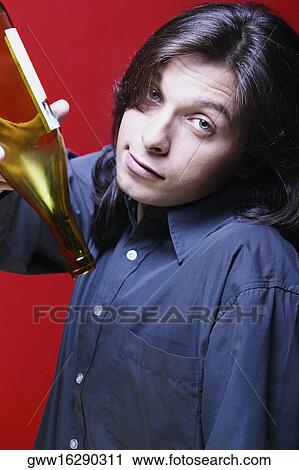 Stock Image - Portrait of a young man holding an empty wine bottle. Fotosearch