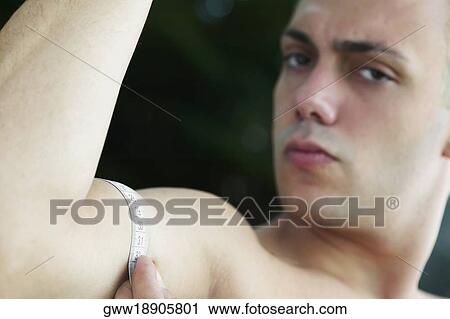 Portrait of a young man measuring his biceps with a measuring tape View Large Photo Image Stock Image - Portrait of a young man measuring his biceps with a measuring tape. Fotosearch