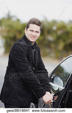 Portrait of a young man opening the door of a car View Large Photo Image Stock Image - Portrait of a young man opening the door of a car. Fotosearch