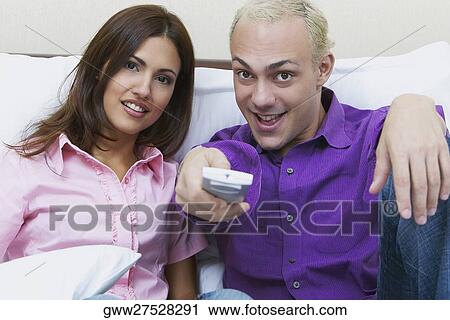 Portrait of a young man operating a remote with a young woman sitting beside him View Large Photo Image Stock Image - Portrait of a young man operating a remote with a young woman sitting beside him. Fotosearch