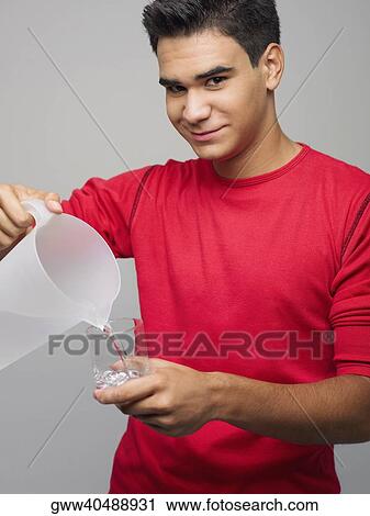 Portrait of a young man pouring water in a glass from a jug View Large Photo Image Stock Image - Portrait of a young man pouring water in a glass from a jug. Fotosearch