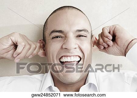 Stock Image - Portrait of a young man pulling his ears. Fotosearch