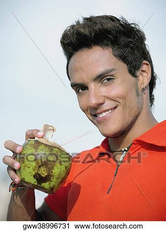 Portrait of a young man sipping juice from a coconut View Large Photo Image Stock Image - Portrait of a young man sipping juice from a coconut. Fotosearch