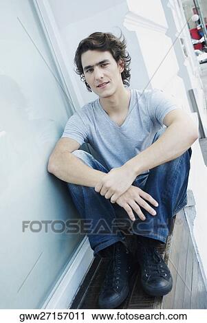 Portrait of a young man sitting with his hands on his knees View Large Photo Image Stock Image - Portrait of a young man sitting with his hands on his knees. Fotosearch