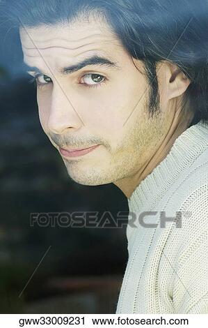 Portrait of a young man smirking behind a glass View Large Photo Image Stock Image - Portrait of a young man smirking behind a glass. Fotosearch
