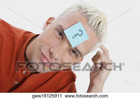 Portrait of a young man smirking with an adhesive note on his forehead View Large Photo Image Stock Image - Portrait of a young man smirking with an adhesive note on his forehead. Fotosearch