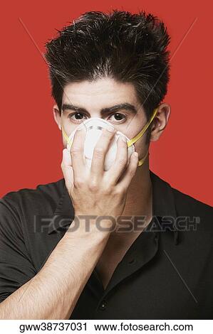 Stock Image - Portrait of a young man wearing a pollution mask. Fotosearch
