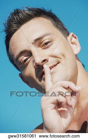 Portrait of a young man with his finger on his lips View Large Photo Image Stock Image - Portrait of a young man with his finger on his lips. Fotosearch