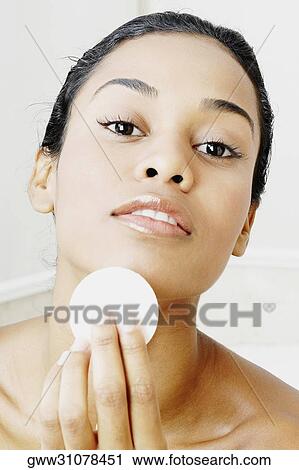 Stock Image - Portrait of a young woman applying face powder. Fotosearch