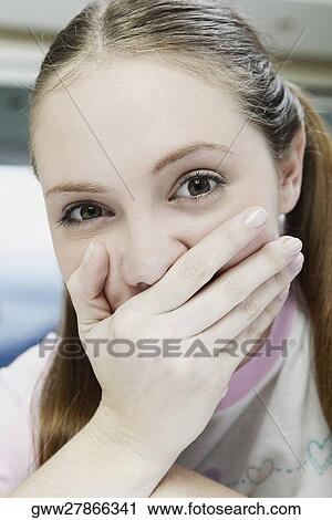 Portrait of a young woman covering her mouth with her hand View Large Photo Image Stock Image - Portrait of a young woman covering her mouth with her hand. Fotosearch