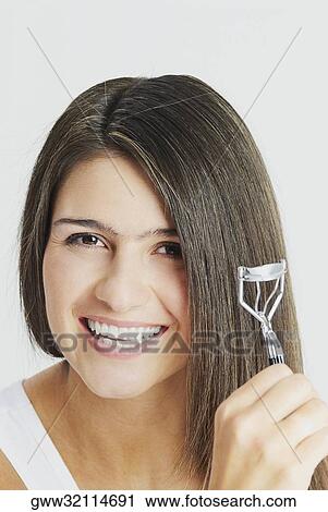 Portrait of a young woman crimping her hair View Large Photo Image Stock Image - Portrait of a young woman crimping her hair. Fotosearch