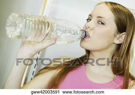 Portrait of a young woman drinking water from a water bottle View Large Photo Image Stock Image - Portrait of a young woman drinking water from a water bottle. Fotosearch