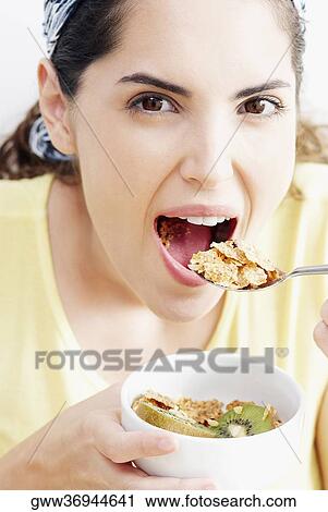 Portrait of a young woman eating a bowl of corn flakes View Large Photo Image Stock Image - Portrait of a young woman eating a bowl of corn flakes. Fotosearch