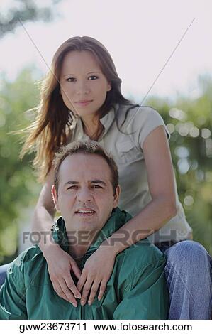 Portrait of a young woman embracing a mid adult man from behind View Large Photo Image Stock Image - Portrait of a young woman embracing a mid adult man from behind. Fotosearch