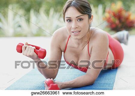 Stock Image - Portrait of a young woman exercising with dumbbells. Fotosearch