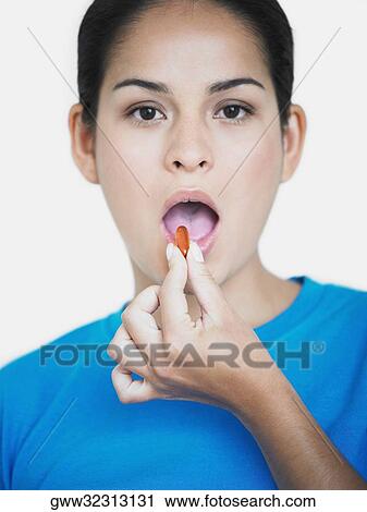Stock Image - Portrait of a young woman having a capsule. Fotosearch
