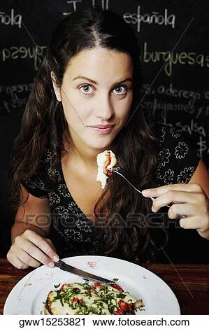 Portrait of a young woman having food in a restaurant View Large Photo Image Stock Image - Portrait of a young woman having food in a restaurant. Fotosearch