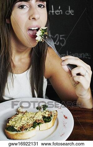 Portrait of a young woman having food in a restaurant View Large Photo Image Stock Image - Portrait of a young woman having food in a restaurant. Fotosearch