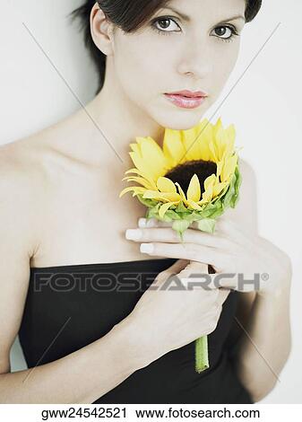 Portrait of a young woman holding a sunflower View Large Photo Image Stock Image - Portrait of a young woman holding a sunflower. Fotosearch