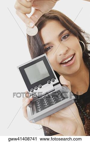 Stock Image - Portrait of a young woman holding a calculator and a coin. Fotosearch