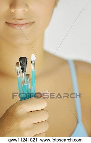 Portrait of a young woman holding make-up brushes View Large Photo Image Stock Image - Portrait of a young woman holding make-up brushes. Fotosearch