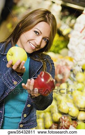 Portrait of a young woman holding two apples and smiling View Large Photo Image Stock Image - Portrait of a young woman holding two apples and smiling. Fotosearch