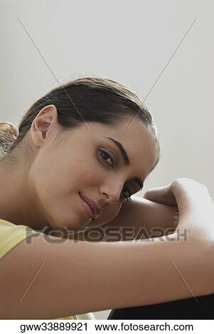 Stock Image - Portrait of a young woman hugging her knees. Fotosearch