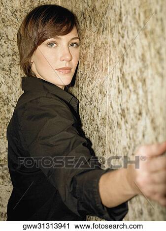 Portrait of a young woman leaning against a wall View Large Photo Image Stock Image - Portrait of a young woman leaning against a wall. Fotosearch