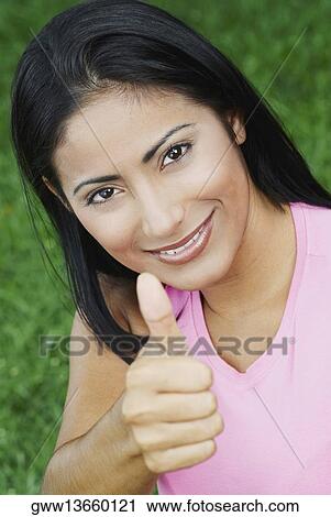 Portrait of a young woman making a thumbs up sign and smiling View Large Photo Image Stock Image - Portrait of a young woman making a thumbs up sign and smiling. Fotosearch