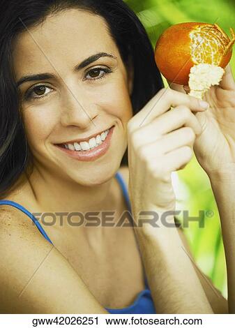 Portrait of a young woman peeling an orange View Large Photo Image Stock Image - Portrait of a young woman peeling an orange. Fotosearch