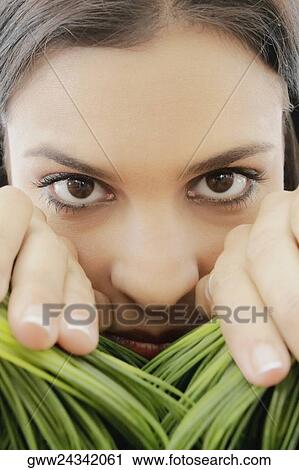 Stock Image - Portrait of a young woman separating wheatgrass with her hands. Fotosearch