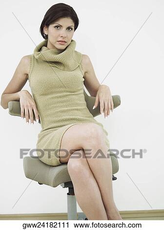 Portrait of a young woman sitting on a chair View Large Photo Image Stock Image - Portrait of a young woman sitting on a chair. Fotosearch