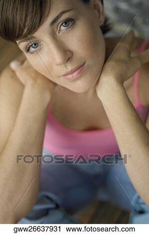 Stock Image - Portrait of a young woman sitting on a hardwood floor. Fotosearch