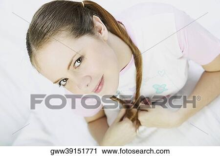 Portrait of a young woman sitting on the bed View Large Photo Image Stock Image - Portrait of a young woman sitting on the bed. Fotosearch