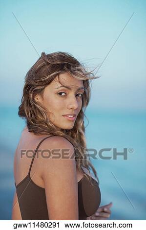 Portrait of a young woman standing on the beach View Large Photo Image Stock Image - Portrait of a young woman standing on the beach. Fotosearch