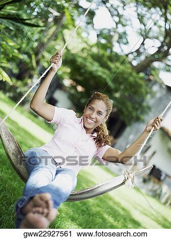 Stock Image - Portrait of a young woman swinging on a swing. Fotosearch