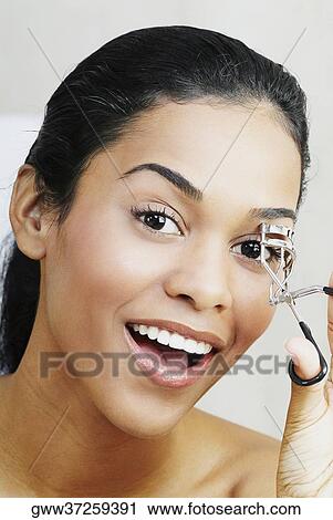 Portrait of a young woman using a eyelash curler View Large Photo Image Stock Image - Portrait of a young woman using a eyelash curler. Fotosearch