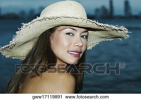 Stock Image - Portrait of a young woman wearing a sunhat. Fotosearch