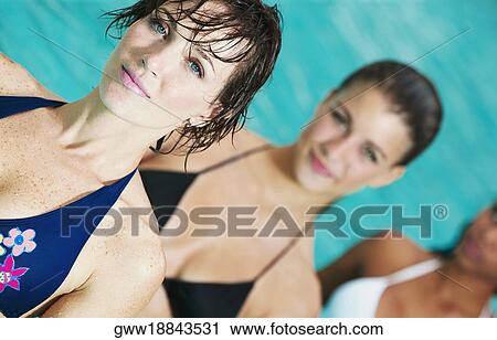 Stock Image - Portrait of a young woman with her friends in a swimming pool. Fotosearch