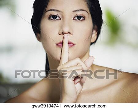 Portrait of a young woman with her finger on her lips View Large Photo Image Stock Image - Portrait of a young woman with her finger on her lips. Fotosearch
