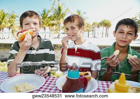 Portrait of two boys and a teenage boy eating food View Large Photo Image Stock Image - Portrait of two boys and a teenage boy eating food. Fotosearch