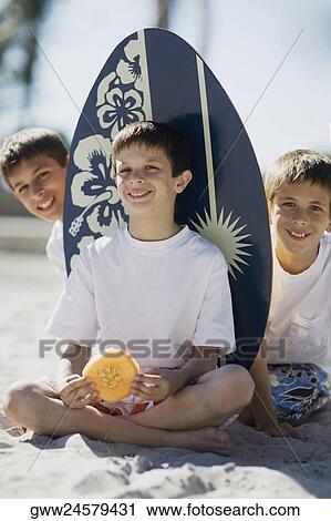 Portrait of two boys and a teenage boy sitting on the beach and smiling View Large Photo Image Stock Image - Portrait of two boys and a teenage boy sitting on the beach and smiling. Fotosearch