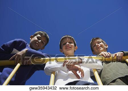 Portrait of two boys and a teenage boy leaning against a railing and smiling View Large Photo Image Stock Image - Portrait of two boys and a teenage boy leaning against a railing and smiling. Fotosearch